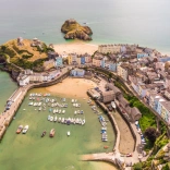 Aerial view of a harbour, two beaches and pastel coloured houses.